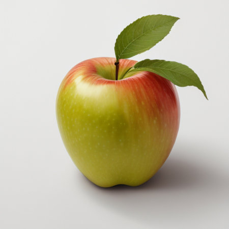 A ripe apple with a green leaf attached, sitting on a white surfaceの素材