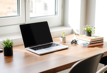 Laptop with blank screen on wooden table near window in modern officeの写真素材