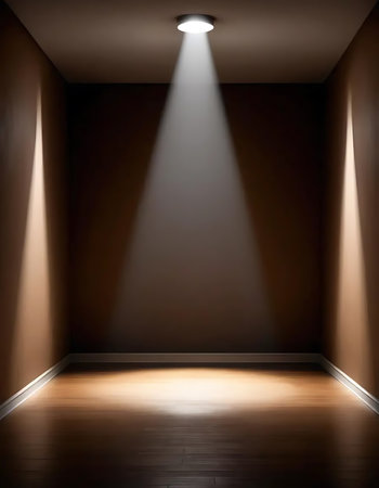 A minimalistic room interior featuring a bright spotlight that casts a beam onto the wooden floor, contrasted against dark walls. The empty space provides a sense of solitude and modern design.の写真素材