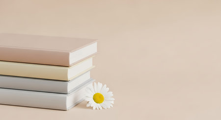 Stack of books and chamomile flower on beige backgroundの写真素材