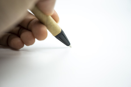Hand holding ballpoint pen pointing on white paper. Selective focus.の写真素材
