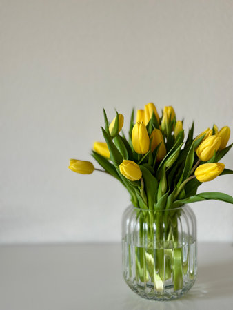 Bouquet of yellow tulips in a vase on the tableの写真素材