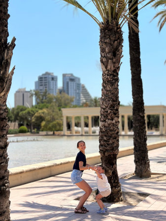 Mother and daughter walking in the park near the palm trees on a sunny dayの写真素材