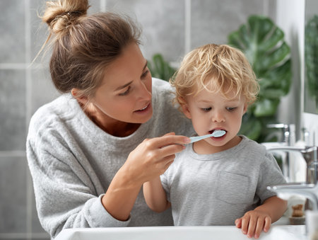 Mother and son brushing teeth in bathroom. Little boy with toothbrushの素材