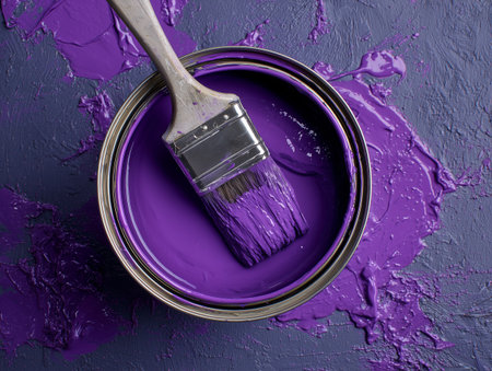 A jar of purple paint with a brush dipped in it on a purple backgroundの素材