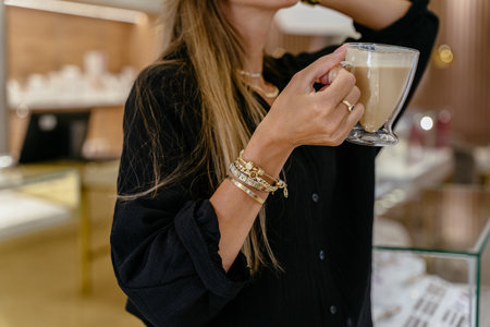 Unrecognizable fashionable woman in golden bracelets, rings, chains during work in a jewelry shop. Successful people in small business concept.の写真素材