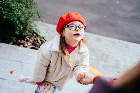 Portrait of little girl wear red beret in eyeglasses with special needs looking at unrecognizable mother.の写真素材