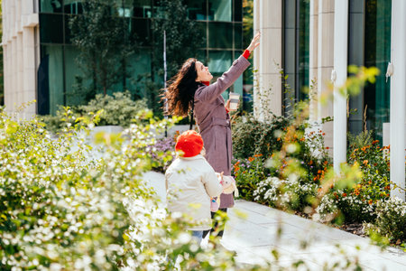 Cute lovely positive brunette mother carrying her happy disabilities daughter. Woman and child enjoy walk autumn sunny day outside.の写真素材