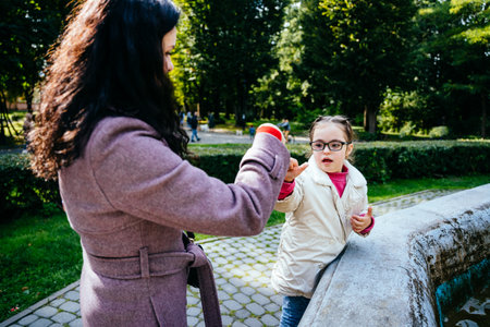 Mother and little daughter high fiving in autumnal park outdoor. Brunette woman and child girl enjoy good day together. Team gesture, moment concept.の写真素材