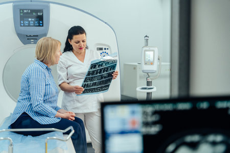 A woman is sitting in a hospital room with a doctor looking at a medical image. The woman is in pain, and the doctor is trying to diagnose her condition. Concept of concern and urgencyの写真素材