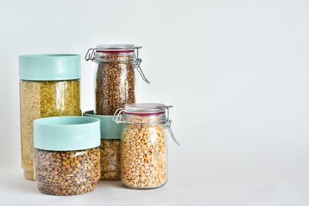 Jars with different types of cereals on a white background. Rice, buckwheat, lentils, peas. place for text. healthy eating concept.の写真素材
