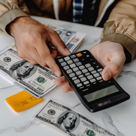 cropped view of man counting money with calculator on table in officeの素材