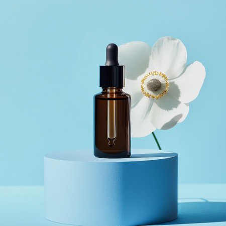 Glass dropper bottle with serum or oil, white flower on blue background.の素材