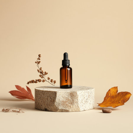 Mockup of a brown glass dropper bottle with a pipette on a stone podium with autumn leaves.の素材