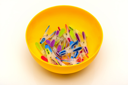 Multicolored clothespins in a yellow bowl.の写真素材