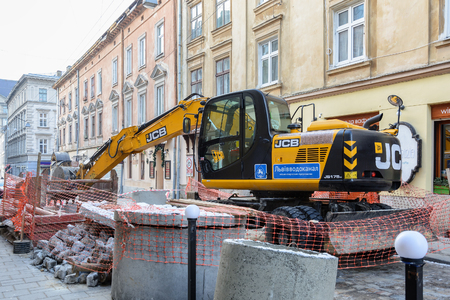 Ukraine, Lviv - December, 17, 2016: Repair of the aqueduct in the city center of Lviv on the narrow street. Construction machinery. Excavation work at the construction site.のeditorial素材