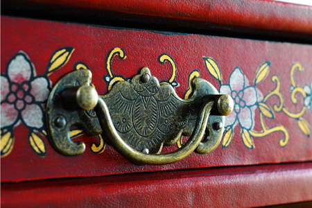 Vintage furniture handle on a red box with a floral pattern.の写真素材