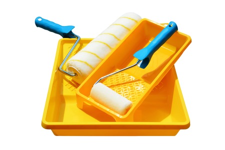 Yellow painting tray and paint roller made of synthetic fiber on the surface of wooden slats. Isolated, white background.の写真素材