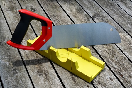 Hand saw and a yellow miter box to make precise mitre cuts in a board.の写真素材