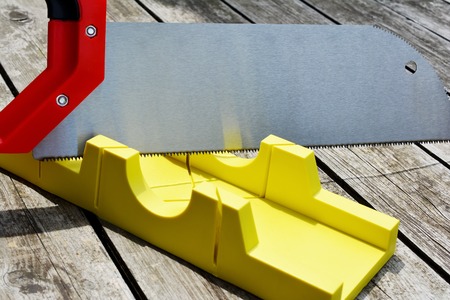 Hand saw and a yellow miter box to make precise mitre cuts in a board.の写真素材