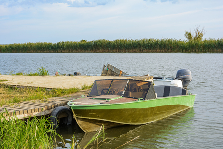 Motor boat near the wooden pier on the river on a summer day.の写真素材