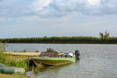 Motor boat near the wooden pier on the river on a summer day.