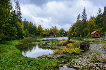 House near the lake in the forest, autumn day.  Leaf fall landscape.の写真素材