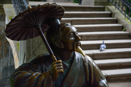 Bronze sculpture of Chinese with umbrella near the "Chinese Bridge" 

in the park. Park "Oleksandriya" in Bila Tserkva, Ukraine.の写真素材