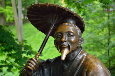 Bronze sculpture of Chinese with umbrella near the "Chinese Bridge" 

in the park. Park "Oleksandriya" in Bila Tserkva, Ukraine.の写真素材