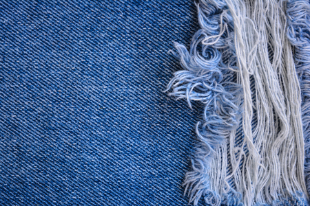 Fragment of jeans trousers with torn, ripped patch, decorated with a hole with threads. Denim background.の写真素材