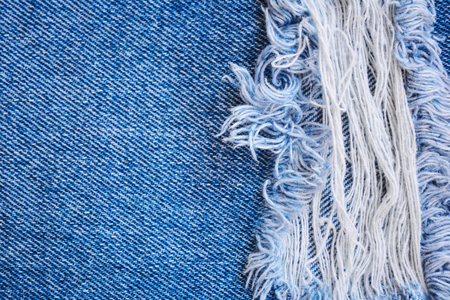 Fragment of jeans trousers with torn, ripped patch, decorated with a hole with threads. Denim background.の写真素材
