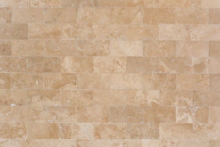 Stone facing of beige wall made of travertine. Texture of masonry.の写真素材
