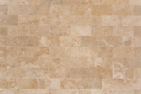 Stone facing of beige wall made of travertine. Texture of masonry.