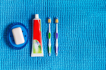 Blue soap dish with white soap, colored toothbrushes and tube of toothpaste.の写真素材