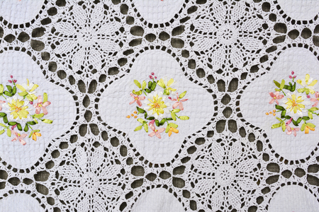 Multi-colored ornate floral pattern on white cotton lace tablecloth.の写真素材
