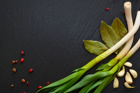 Garlic, bay leaf, onions and berries of barberry on on black slate board, plate or tray.の写真素材