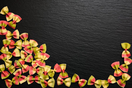Traditional italian flour product, colored pasta in the form of bow on board, plate or tray of black...
