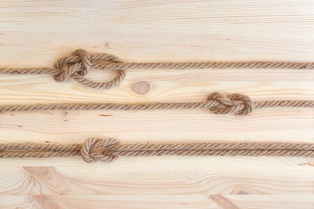 Marine knots used in yachting: figure eight knot, square knot, bowline knot. Nautical knots on wooden background.の写真素材