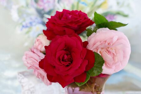 Bouquet of lively red and pink roses in a glass vase, floral background. Flowers of hybrid tea roses with scarlet and pink delicate petals.の写真素材