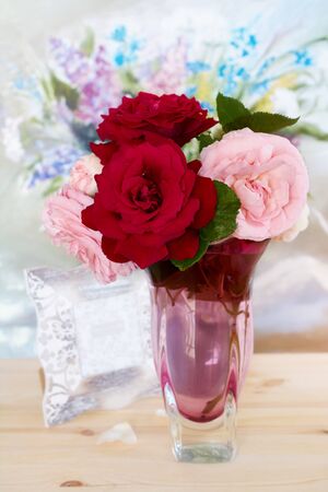Bouquet of lively red and pink roses in a glass vase on the table, floral background. Flowers of hybrid tea roses with scarlet and pink delicate petals.の写真素材