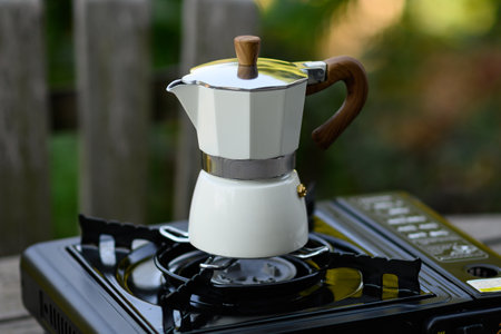 Moka pot on a gas burner. Geyser coffee maker on a camping gas stove. Making coffee outdoors in the garden.の写真素材