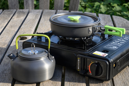 Frying pan on a camping gas stove and a kettle. Cooking outdoors in the garden. Travel kettle, frying pan and stove.の写真素材