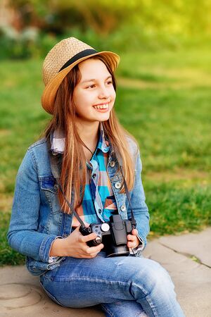 Girl wearing denim coat, straw hat and jeans walking around city center and taking photosの写真素材