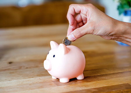 Woman putting coins to piggi bank