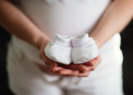 Pregnant woman holding baby shoes