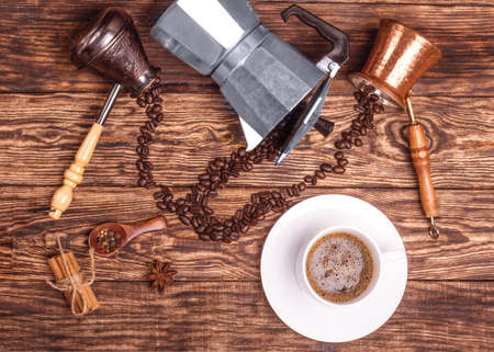 Cup of coffee, three coffeepots, cinnamon, anise, coffee beans on a wooden tray.  View from the top.の写真素材