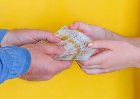 people passing money each other on yellow backgroundの写真素材
