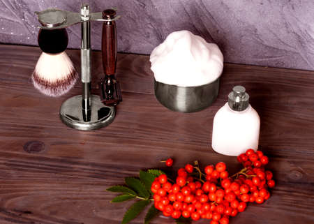 Razors, brush, foam, perfume and rowan  on a wood background.の写真素材