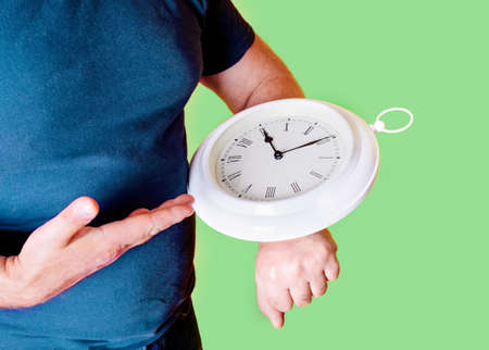 man holding clock and pointing to them on green backgroundの写真素材