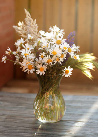 Some wildflowers in a vase on wooden backgroundの写真素材